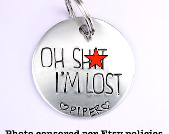 May include: A silver dog tag with a red star and the text "Oh Shit I'm Lost" and the name "Piper" engraved on it.