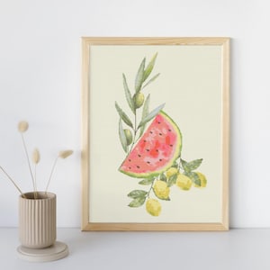 May include: A framed watercolor print featuring a slice of watermelon, lemons, and olive branches. The watermelon is pink with black seeds, the lemons are yellow, and the olives are green. The artwork is set against a cream background.