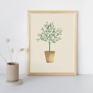 Puede incluir: Una impresión artística enmarcada que presenta una ilustración en acuarela de un pequeño árbol en maceta. El árbol tiene hojas verdes y un tronco marrón, sobre un fondo crema. El marco es de madera clara, y la estética general es minimalista y natural.