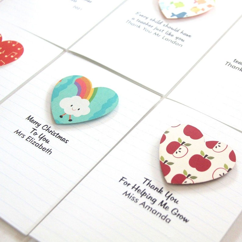 May include: A set of six heart-shaped cards with different designs and messages. The cards are printed with lined paper and have a white background. The messages include "Merry Christmas to You", "Thank You", "For Helping Me Grow", and "Every child should have a teacher just like you".