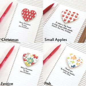May include: Four handmade cards with different designs. Each card features a heart-shaped paper cutout with a different pattern. The cards have handwritten messages on them. The cards are on a lined notebook page.