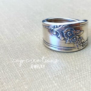 May include: A silver ring made from a vintage spoon with a floral design. The ring is wide and has a curved shape.