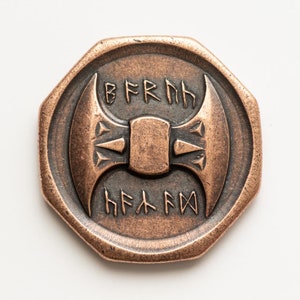 May include: A copper-colored, octagonal coin with a raised design of a double-headed axe and the text "BFRHH HFKFW".
