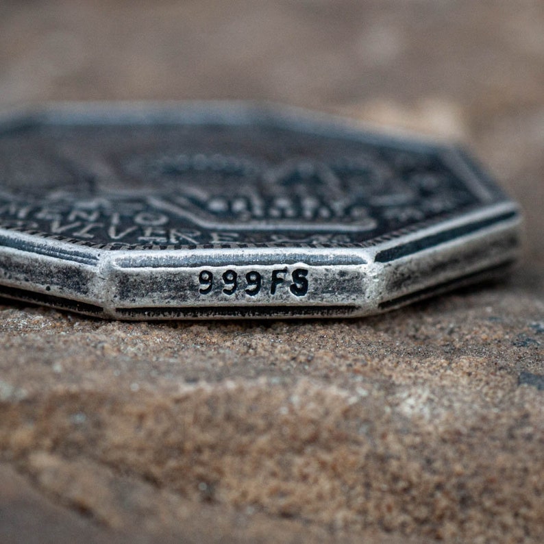 May include: Close-up of a silver coin with a detailed design and the inscription "999 FS" on the edge.