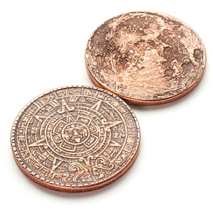 May include: Two copper coins, one with a detailed design of the Aztec calendar and the other with a textured surface.
