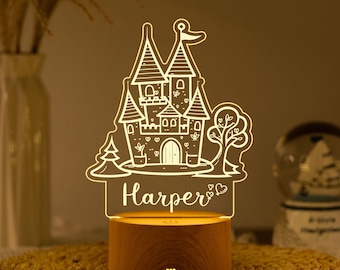 Puede incluir: Una luz nocturna LED decorativa con un diseño de castillo y el nombre "Harper" grabado en la base. El castillo se ilumina con un brillo suave y se asienta sobre una base de madera. Esta luz está diseñada para ser una adición encantadora a cualquier habitación.