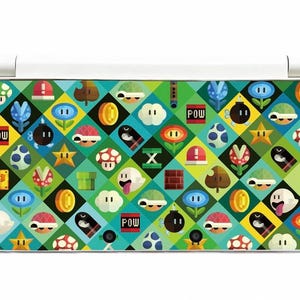Puede incluir: Una funda para Nintendo 3DS con un colorido diseño de personajes e iconos de Super Mario Bros. El diseño incluye champiñones, monedas, estrellas y la palabra "POW" en un recuadro rojo, sobre un fondo de diamantes turquesa y verdes.