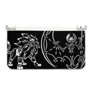 May include: Black and white Nintendo 3DS console featuring a graphic design of a lion-like creature and a bat-like creature. The console has a white top and a black bottom with the graphic design.