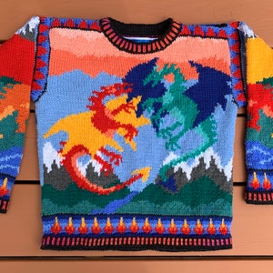 Könnte beinhalten: Ein gestrickter Pullover mit einem farbenfrohen Design aus zwei kämpfenden Drachen in einer Berglandschaft. Der Pullover hat einen schwarzen Rundhalsausschnitt und ein Farbschema in Rot, Orange, Gelb, Grün, Blau und Weiß.