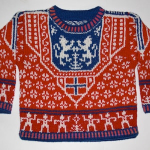 May include: A red, white, and blue knitted sweater with a traditional Scandinavian design. The sweater features a central crest with two lions and a cross, surrounded by a repeating snowflake pattern.