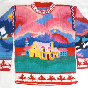 May include: A colorful knitted sweater with a scene of a house, a lighthouse, and a sailboat on the front. The sweater has a red, white, and blue border with a maple leaf design.