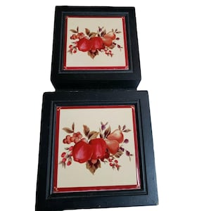 May include: Two black wooden boxes with red trim and a white background. Each box has a tile with a floral design featuring red apples, pears, and green leaves.