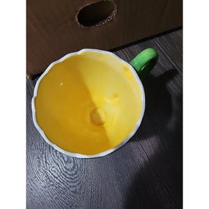 May include: A white ceramic mug with a black handle and the text "But First, Coffee" in a handwritten style. The mug is on a white surface. The mug is approximately 4 inches tall.