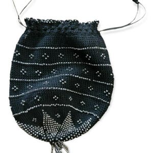 May include: A black beaded drawstring bag with a decorative beaded fringe. The bag features horizontal rows of small silver beads and a detailed beaded design at the bottom. The drawstring is black.