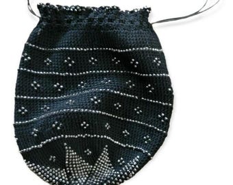 May include: A black beaded drawstring bag with a decorative beaded fringe. The bag features horizontal rows of small silver beads and a detailed beaded design at the bottom. The drawstring is black.