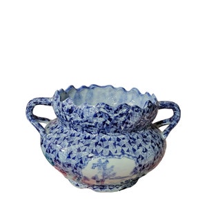 May include: A blue and white ceramic planter with a scalloped rim and two handles. The planter has a floral and geometric design.