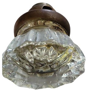 May include: A clear glass door knob with a faceted design and a brass base.