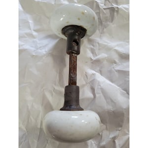 May include: White porcelain door knob with a brass base and a wooden spindle.