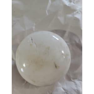 May include: A white, round, ceramic knob with a crack running down the side. The knob has a slightly textured surface and appears to be vintage.