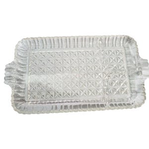 May include: A clear glass serving tray with a diamond pattern and a raised edge. The tray has two small side handles.