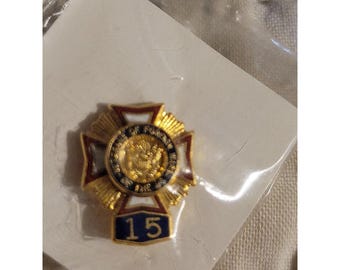 Könnte beinhalten: Ein goldfarbener Ansteckpin mit Kreuzdesign, mit roten, weißen und blauen Emaille-Akzenten. Die Mitte hat ein rundes Emblem mit Text und einem goldenen Emblem. Die Zahl "15" wird unten angezeigt.