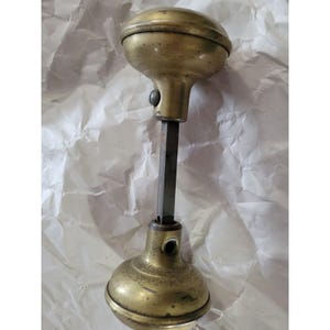 May include: A vintage brass door knob with a round, domed shape and a long, straight spindle. The knob is in good condition with a slight patina.