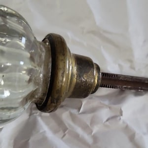 May include: A vintage glass doorknob with a brass base and a threaded metal rod.