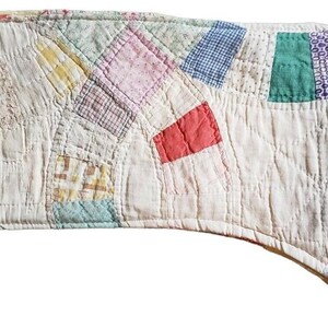 May include: A white quilted stocking with a patchwork design featuring various colors, including pink, green, blue, and red.
