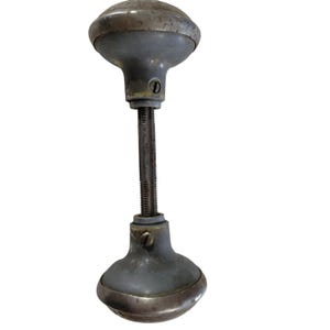 May include: A vintage door knob with a brass finish and a gray metal body. The knob has a threaded shaft and two screws.