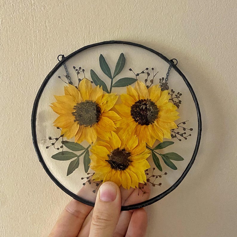 Op de afbeelding: Set van drie keramische mokken met een gespikkelde, cr&egrave;mekleurige glazuur. Elke mok heeft een handgeschilderd bloemmotief in blauw, groen en geel. De mokken hebben een eenvoudige, afgeronde vorm en een handvat.
