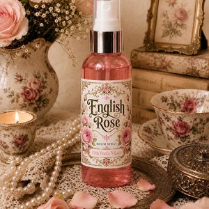 Könnte beinhalten: Eine durchsichtige Kunststoffsprühflasche gefüllt mit rosa Flüssigkeit, mit einem Etikett mit dem Text English Rose, ROOM SPRAY und Pink Petals N Lace, versehen mit einem silbernen Verschluss und einer transparenten Kappe, auf einem Metalltablett.