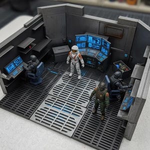 May include: A detailed miniature diorama of a futuristic control room. The scene features several figures in space suits and uniforms, working at computer consoles with glowing blue screens. The room has a metallic gray color scheme with a gridded floor.