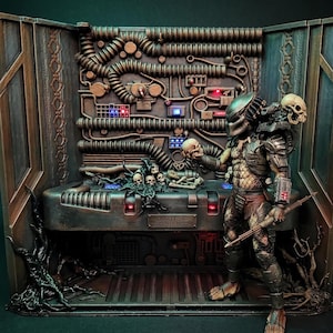 May include: A Predator action figure stands in a detailed diorama labeled YAUTJA TROPHY ROOM. The scene features a metallic wall with pipes, glowing lights, and a console displaying skulls and bones. The figure holds a skull and a staff.