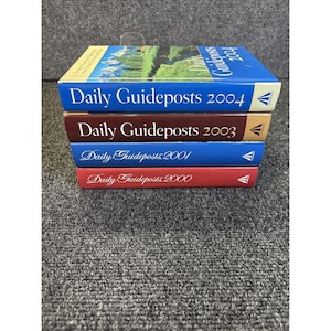 Peut inclure: Une pile de quatre livres "Daily Guideposts". Le livre du dessus est bleu avec "Daily Guideposts 2004" imprimé sur la couverture. En dessous, un livre marron avec "Daily Guideposts 2003". Les deux autres livres sont bleus et rouges.