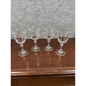Pode incluir: Um conjunto de quatro taças de vinho em vidro transparente, cada uma com um cálice liso e arredondado, uma haste fina com um nó decorativo facetado no centro e uma base circular. As taças são transparentes e de design uniforme.