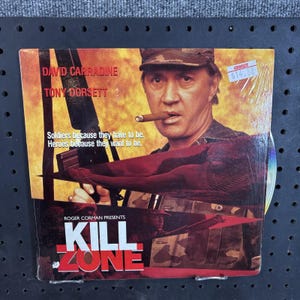 May include: A DVD of the movie "Kill Zone" featuring David Carradine and Tony Dorsett. The cover art shows a man in a military cap with a cigar, holding a weapon. Text includes "Soldiers because they have to be. Heroes because they want to be."