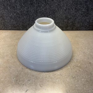 Op de afbeelding: Een witte, kegelvormige glazen lampenkap met een textuur, rasterachtig patroon. De lampenkap heeft een afgeronde basis en een cilindrische opening aan de bovenkant. Geschikt voor verschillende armaturen.