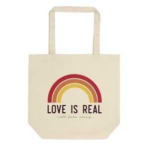 May include: A beige tote bag with a rainbow design and the text "LOVE IS REAL not fade away".