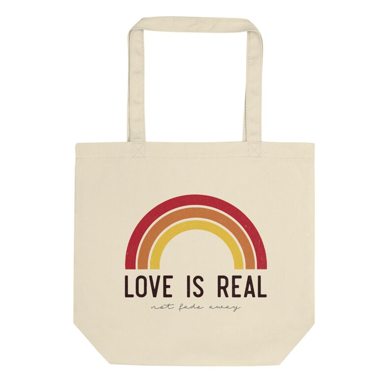 May include: A beige tote bag with a rainbow design and the text "LOVE IS REAL not fade away".