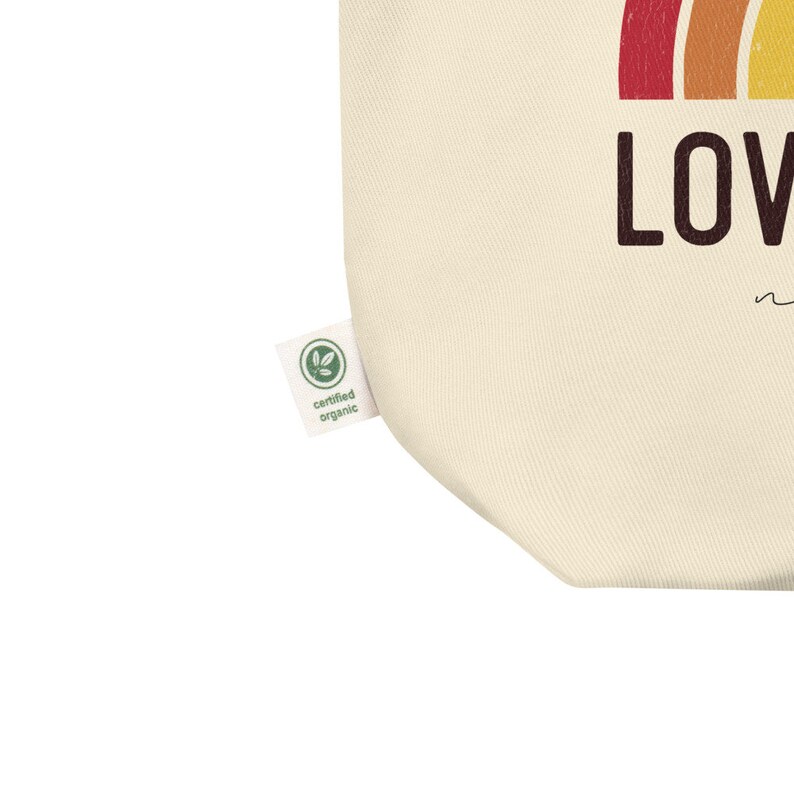 May include: A beige tote bag with a rainbow design and the word "LOVE" in black text. The bag has a green "certified organic" label.