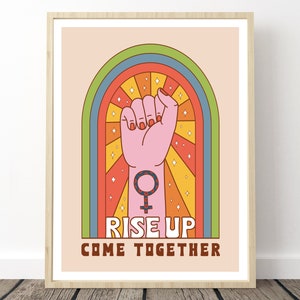 Può includere: Un poster in stile retrò con un pugno alzato e il simbolo femminile al centro. Il pugno è rosa e il simbolo è nero. Lo sfondo è un arcobaleno con uno schema di colori giallo, arancione, rosso, blu e verde. Il testo "Rise Up Come Together" è in basso sul poster.
