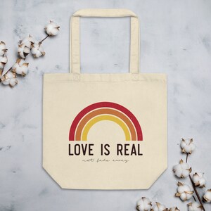 May include: A beige tote bag with a rainbow design and the text "LOVE IS REAL not fade away".