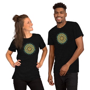 May include: Two people wearing black t-shirts with a green and gold mandala design. The mandala features the Om symbol and the text "Everything's alright, so just hold that thought. The light doesn't pick and the sun doesn't choose."