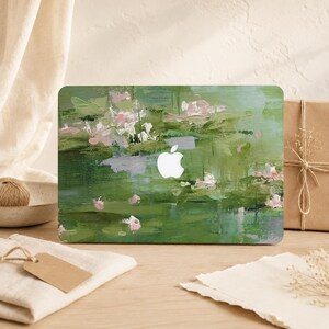 May include: A laptop skin featuring an abstract oil painting design with layered brushstrokes in various shades of sage, olive, and forest green, accented by soft touches of pale pink and white, centered around a white Apple logo cutout.
