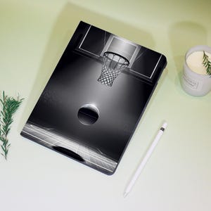 May include: Black and white basketball court design on a tablet case. The case features a basketball hoop, a basketball, and court lines. A white stylus and a lit candle are also visible.