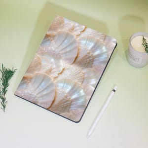 Può includere: Una custodia per laptop bianca con un motivo di conchiglie iridescenti. La custodia è realizzata in un materiale morbido e resistente ed è perfetta per proteggere il tuo laptop da graffi e urti.