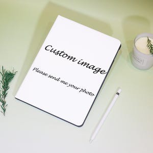 Może przedstawiać: Biały notatnik z czarną obwódką, z tekstem "Custom image, Please send me your photo." Biały rysik i zapalona świeca z zielenią są również obecne na jasnozielonej powierzchni.