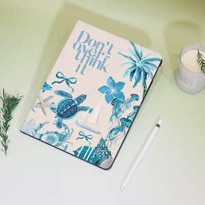 May include: A light beige iPad case with a blue and white nautical design. The case features a sailboat, a turtle, a starfish, a crab, a seashell, a jellyfish, a palm tree, and a flower. The text "Don't overthink it" is printed on the case.