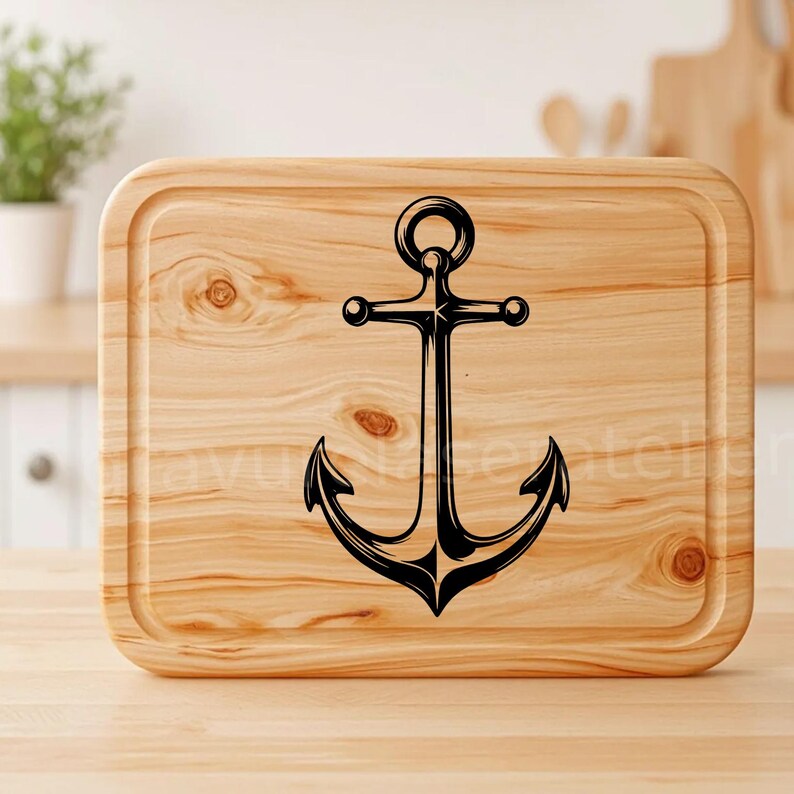 Puede incluir: Una tabla de cortar de madera con un dise&ntilde;o de ancla negra. La tabla tiene una veta de madera natural y un borde ligeramente redondeado.