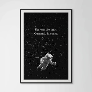 Könnte beinhalten: Schwarz-Weiß-Druck mit einem Astronauten im Weltraum vor einem Sternenhimmel. Der Text lautet: „Sky was the limit. Currently in space.“